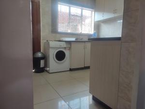 a kitchen with a washing machine in a kitchen at Casa Línda Guest House in Newcastle