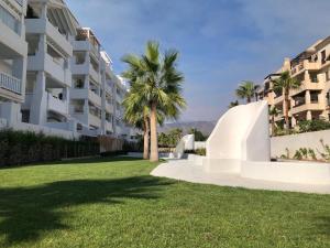 césped frente a un edificio con palmeras en Villa Bobita-Marina Golf-Playa Granada en Motril