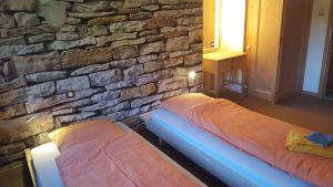 2 camas en una habitación con una pared de piedra en Haus Corina en Klosters