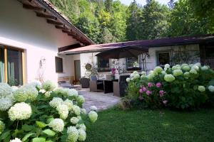 einen Garten mit weißen Blumen und einem Sonnenschirm in der Unterkunft Landhaus Heuchen in Reit im Winkl