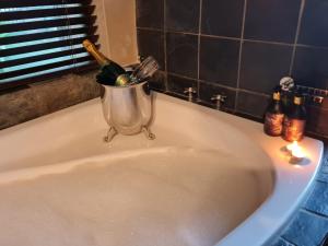 a sink with a bucket with wine bottles on it at Tranquil Garden Nest in Nelspruit