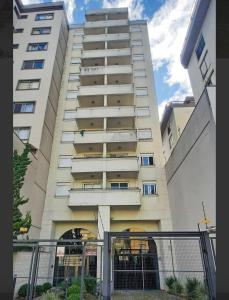a tall white building with a fence in front of it at Pasqualetto in Caxias do Sul