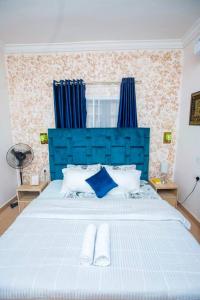 a large bed with a blue headboard in a bedroom at AJI Luxury 3BED Apartment (Ijegun, Lagos) in Lagos