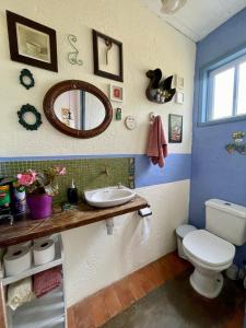 une salle de bain avec toilettes, lavabo et miroir dans l'établissement Casa das Orquídeas, à Lavras Novas