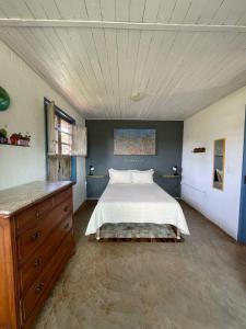 1 dormitorio con cama blanca y tocador de madera en Casa das Orquídeas en Lavras Novas