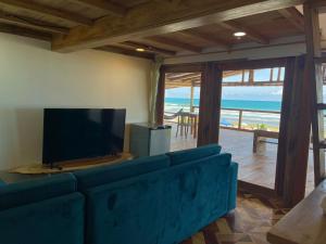 a living room with a blue couch and a television at El Mangle Suite Front Beach in Ayampe