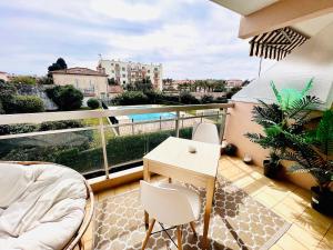 a balcony with a table and chairs on a balcony at LES PALMIERS - Appartement avec piscine proche plage in Antibes