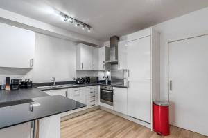 a kitchen with white cabinets and a red refrigerator at Canning Town Pied-à-Terre in London