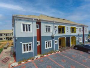 un edificio blu e bianco con un'auto in un parcheggio di AJI Warm 2BED Apartment (Ijegun, Lagos) a Lagos