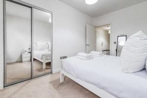 a white bedroom with a mirror and a bed at Canning Town Pied-à-Terre in London