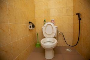 a bathroom with a toilet with a green hose at AJI Warm 2BED Apartment (Ijegun, Lagos) in Lagos
