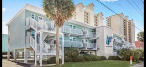 a large apartment building with a palm tree in front of it at Bill’s at Gulf Shores in Gulf Shores