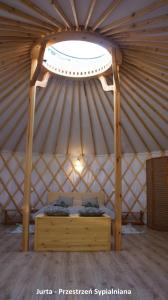 uma cama de madeira numa tenda com uma janela em Domek i jurta nad rzeką em Kościerzyna