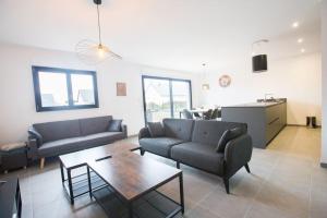 un soggiorno con divani e tavolo e una cucina di Villa en bord de mer SPA / Sauna (N) a Bretteville-sur-Ay