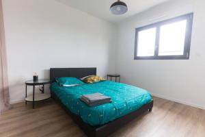 una camera da letto con un letto con un piumone blu e una finestra di Villa en bord de mer SPA / Sauna (N) a Bretteville-sur-Ay Altre 17 foto