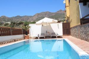 einen Pool mit Sonnenschirm, Stühlen und Sonnenschirm in der Unterkunft Casa Julia y Chloé in Molvízar