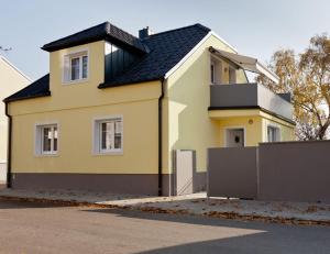 ein gelbes Haus mit schwarzem Dach in der Unterkunft Ferienhaus Burgenland in Mönchhof