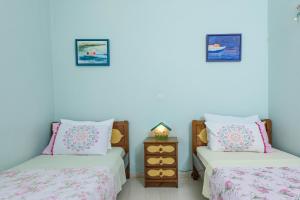 a room with two beds and a night stand with two lamps at Aegina's Flowers house in Aegina Town