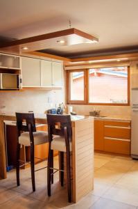 uma cozinha com 2 cadeiras e um balcão com um lavatório em Los Robles Apart & Spa em San Carlos de Bariloche