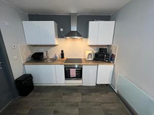 a small kitchen with white cabinets and a sink at Pine Studio in Blackpool