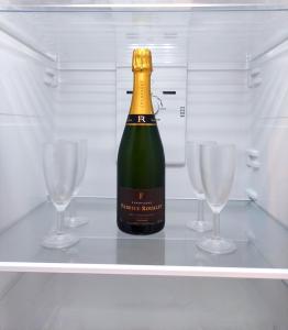 a bottle of champagne in a refrigerator with two glasses at Groom Épernay - Le Petit Tonnelier in Épernay