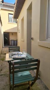 una mesa verde con platos y copas de vino. en Le Rayon de Soleil de Paris Saint-Brice CDG, en Saint-Brice-sous-Forêt