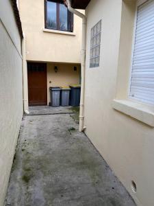 un callejón que conduce a un edificio con una puerta y cubos de basura en Le Rayon de Soleil de Paris Saint-Brice CDG, en Saint-Brice-sous-Forêt