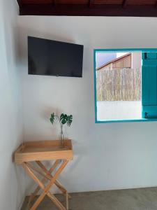 a television on a wall next to a wooden table at CHALÉ NAMORADA PATACHO in Pôrto de Pedras