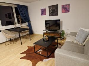 ein Wohnzimmer mit einem Sofa, einem TV und einem Tisch in der Unterkunft 1 Zimmer Appartement im SI Centrum Stuttgart in Stuttgart