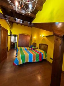 - une chambre jaune avec un lit coloré dans l'établissement Casa de Aldea el Pontón, à Cue