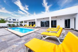 un patio con sillas amarillas y una piscina en Casa Eden naturist area, full privacy, relax and private pool en Charco del Palo