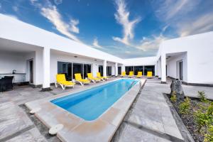 a swimming pool with yellow chairs and a house at Casa Eden naturist area, full privacy, relax and private pool in Charco del Palo