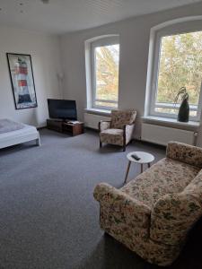 a living room with a couch and a tv and two windows at Haus Regine in Rendsburg