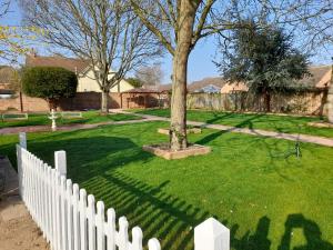 a white picket fence in a yard with a tree at The George & Dragon Hotel in Long Melford