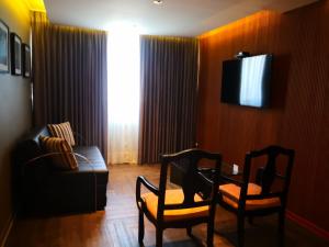 a living room with two chairs and a couch and a television at Hotel Las Lomas in Lima