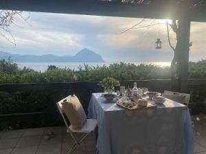 einen Tisch mit einem weißen Tischtuch und Meerblick in der Unterkunft Pittalumari Makari in Macari