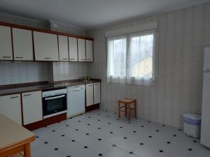 a kitchen with white cabinets and a stove and a window at La Huertina in Cangas de Onís