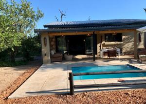 a swimming pool in front of a house at Rooibos Luxury Bush Cottage in Hoedspruit