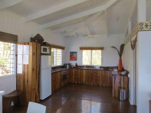 a kitchen with wooden floors and a white refrigerator at Beachfront Villa - House of Bamboo, Infinity Pool in Savusavu