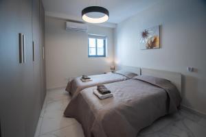 a white bedroom with two beds and a window at Seaside Luxury Apartment in St. Paul's Bay