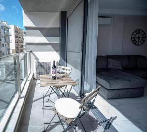 a balcony with a table and chairs and a couch at Seaside Luxury Apartment in St Paul's Bay