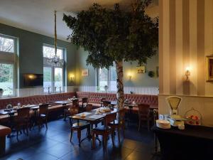 a dining room with tables and a tree in the middle at Hotel Groote Engel in Emlichheim