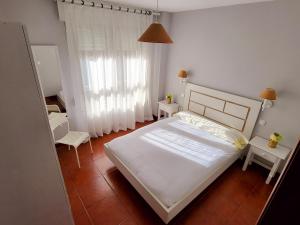 - une chambre avec un lit, deux tables et une fenêtre dans l'établissement Apartamentos San Vicente Playa, à San Vicente de la Barquera