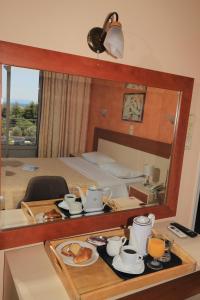 Pokój hotelowy ze stołem z jedzeniem i lustrem w obiekcie IKAROS Hotel ELLINIKO w Atenach