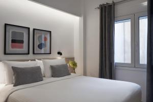 ein Schlafzimmer mit einem großen weißen Bett und einem Fenster in der Unterkunft Parthenon Apartment in Athen