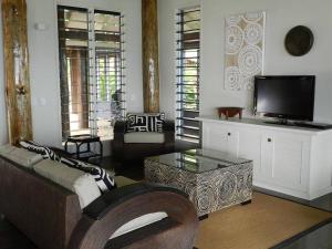 a living room with a couch and a tv at Beachfront Villa - Pod House, Private Plunge Pool in Savusavu