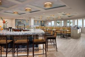 a restaurant with a long bar with tables and chairs at Bethany Beach Ocean Suites Residence Inn by Marriott in Bethany Beach