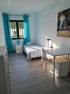 1 dormitorio con cama, escritorio y mesa en Arrecife-Playa del Reducto Apartment, en Arrecife