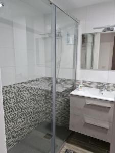 y baño con ducha acristalada y lavamanos. en Arrecife-Playa del Reducto Apartment, en Arrecife