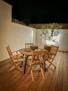 une table et des chaises en bois sur une terrasse en bois dans l'établissement La Porte Rouge - The Red Door, à Audenarde